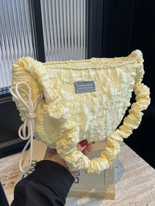 Fashionable pale yellow pleated cloud bag with metallic tag and soft braided details