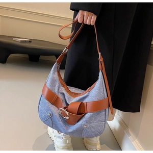 Détail du sac hobo en denim bleu avec sangle en cuir marron et boucle argentée