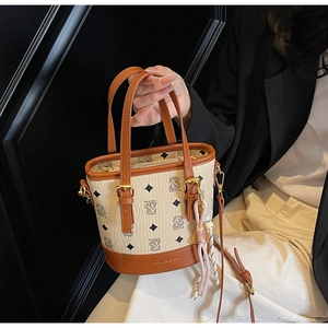 Close-up of beige bucket bag featuring bear print pattern and textured leather details