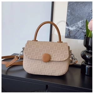 Detail of minimalist beige crossbody bag featuring textured grid pattern and round buckle