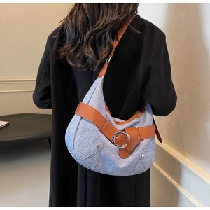 Détail du sac hobo en jean bleu clair avec bandoulière en cuir brun et boucle argentée