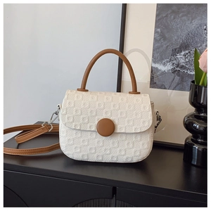Detail of cream jacquard square bag with brown leather handles and silver hooks