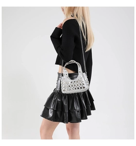 Borsa a secchiello argento stile Y2K con rivetti e catena su un outfit nero