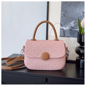 Detail of pink textured crossbody bag with brown handle and golden metal buckles