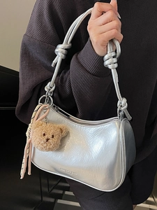 Minimalist silver underarm bag for women with knotted straps and a plush bear pendant