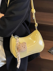 Minimalist bright yellow half-moon shoulder bag with a cute bear charm and knot strap