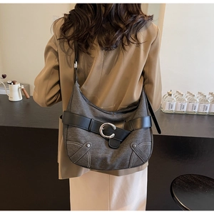 Détail d'un sac en denim avec boucle métallique en C vintage et surpiqûres blanches