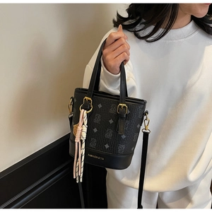 Detail of black bucket bag featuring litchi grain texture and bear pattern prints