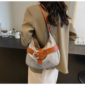 Détail du sac bandoulière croissant en tissu gris avec sangle en cuir brun et boucle métal