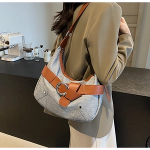 Détail de la texture en denim gris avec sangle en cuir marron et boucle anneau argenté