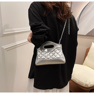 Dettaglio di una borsa trapuntata argento metallizzato con tracolla a catena su modella