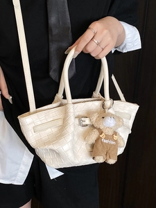 Elegant white woven tote bag with adjustable strap and cute teddy bear charm for women