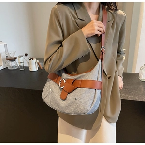 Détail du sac fourre-tout en denim gris avec sangle en cuir marron et boucle métallique
