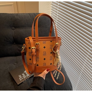 Detail of brown bucket bag with bear print, silk scarf charm and adjustable strap