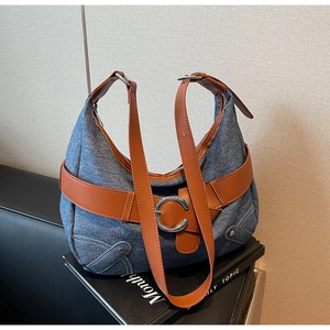 Détail du sac demi-lune en jean avec lanières en cuir marron et boucle en C argentée