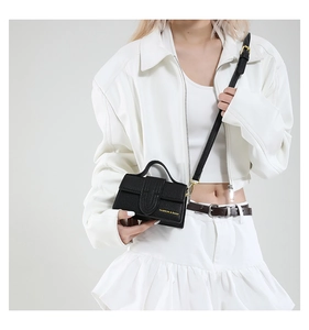 Detailed view of black mini crossbody bag with litchi texture and gold hardware on a model
