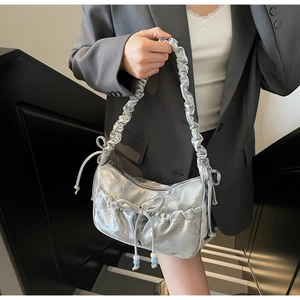 Detailed view of metallic silver pleated shoulder bag with chic bow and bead accents