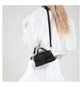Detail showing high-quality black lychee texture leather and gold metal hooks on crossbody bag