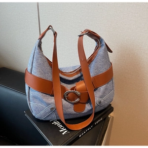 Gros plan détaillé du sac hobo en jean bleu avec garniture en cuir brun et boucle argentée