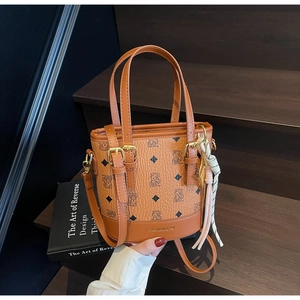 Detailed view of brown leather bucket bag with bear print on a wooden staircase