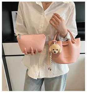Détail du sac seau rose en cuir grainé avec un petit pendentif de chien en peluche