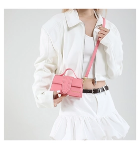 Detailed close-up of a mini pink crossbody bag featuring gold metal hardware and leather texture