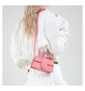 Detailed side view of a light pink mini crossbody bag worn by a model in lifestyle setting