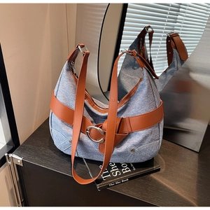 Gros plan du sac hobo vintage en denim bleu avec garniture en cuir brun et boucle en métal