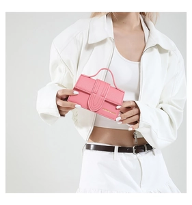 Detail of pink lychee textured mini handbag with U-shaped buckle and gold logo lettering