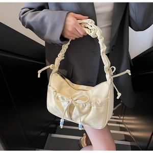 Detail of a creamy white pleated handbag with ribbon bow and elegant beaded drawstring
