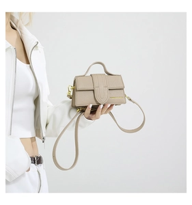 Detail of beige litchi grain leather mini bag with gold hardware and fashion text