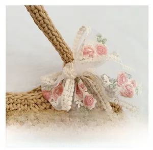 Detail of woven tote bag featuring lace bow with delicate floral embroidery