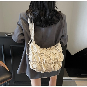 Detailansicht der cremefarbenen Rafftasche mit plissierter Textur und Schulterfalten