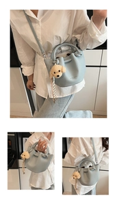 Détail du sac seau bleu clair avec pendentif peluche et finition cuir grainé lychee