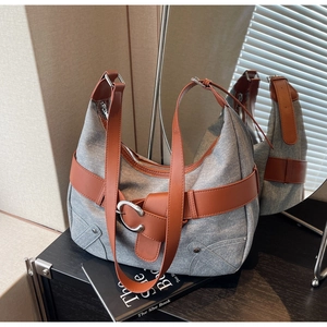 Gros plan d'un sac cabas en denim gris avec lanières en cuir marron et boucles argentées