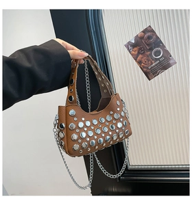 Dettaglio della borsa a secchiello in pelle marrone con borchie tonde e tracolla a catena