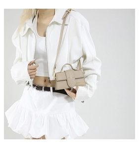 Detail of beige small square crossbody bag with pebble grain leather and gold lettering