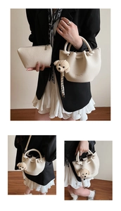 Vue détaillée du sac seau crème avec texture litchi et pendentif de chiot mignon