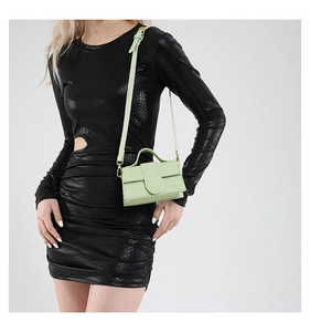 Detail view of mint green mini square crossbody bag with textured leather and gold logo