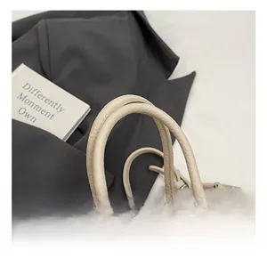 Detailed macro shot of the durable double top handles on this beige pebbled leather bag