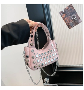 Dettaglio borsa a secchiello in pelle rosa con borchie argento e tracolla a catena
