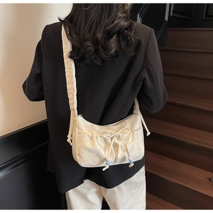 Detail of off-white ruched nylon shoulder bag with drawstring bow and blue bead accents