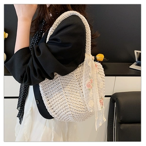 Detail of hand-woven cream tote bag with floral lace scarf accessory on shoulder
