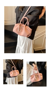 Detail view of pink lychee leather handbag with pearl zipper and cute doll charm