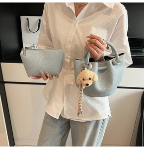 Détail du sac seau bleu clair motif litchi avec pendentif en peluche ours jaune mignon