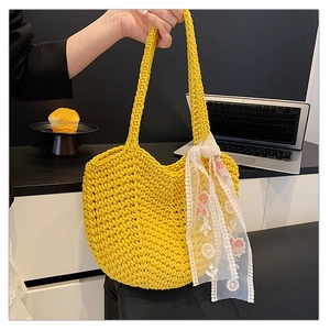 Close-up of a yellow woven tote bag with a white floral lace scarf on a table