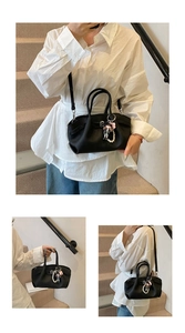 Detail of black lychee grain leather bag with decorative doll and pearl pendant