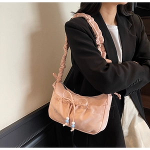 Detail of pink pleated underarm bag with drawstring bow and contrasting beads