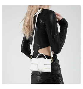 Close-up of a white mini square handbag with lychee texture and gold metal hardware