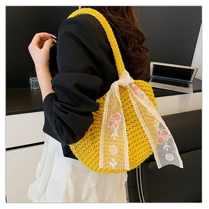 Detail of yellow woven tote bag featuring white lace scarf with pink rose embroidery